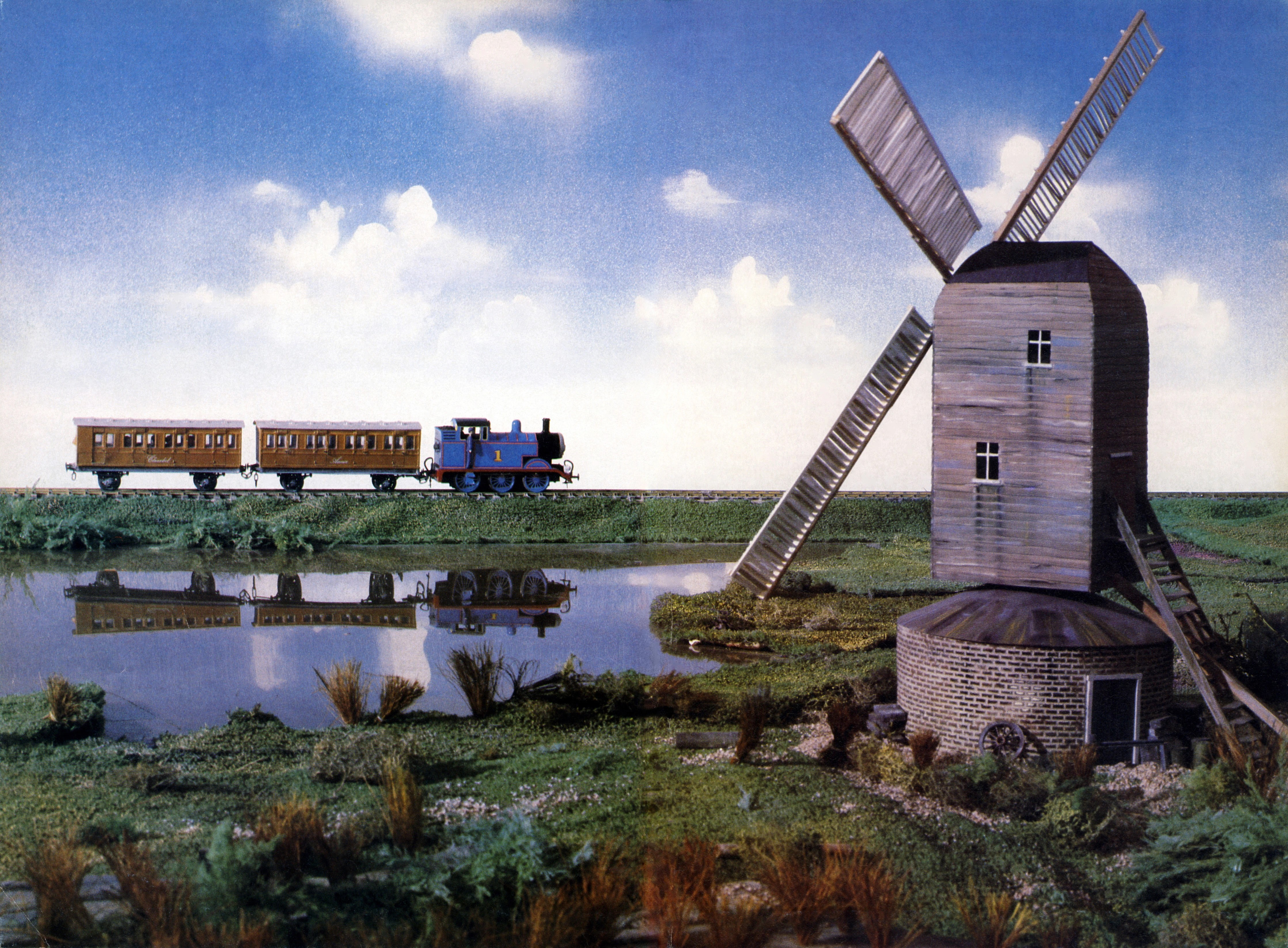 Image example from the show "Thomas the Tank Engine & Friends". A promotional image for the first season (1984) of Thomas with two passenger carriages passing the windmill and pond. Copyright belongs to Mattel/Hit Entertainment. Based on The Railway Series by the Rev. W. Awdry and adapted for the screen by Britt Allcroft